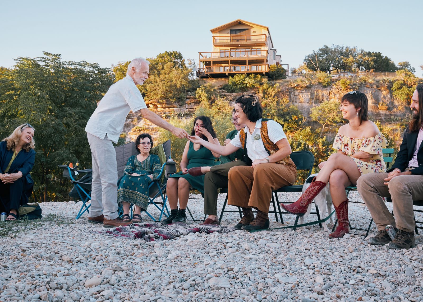 Guests laughing in a circle of camp chairs at golden hour