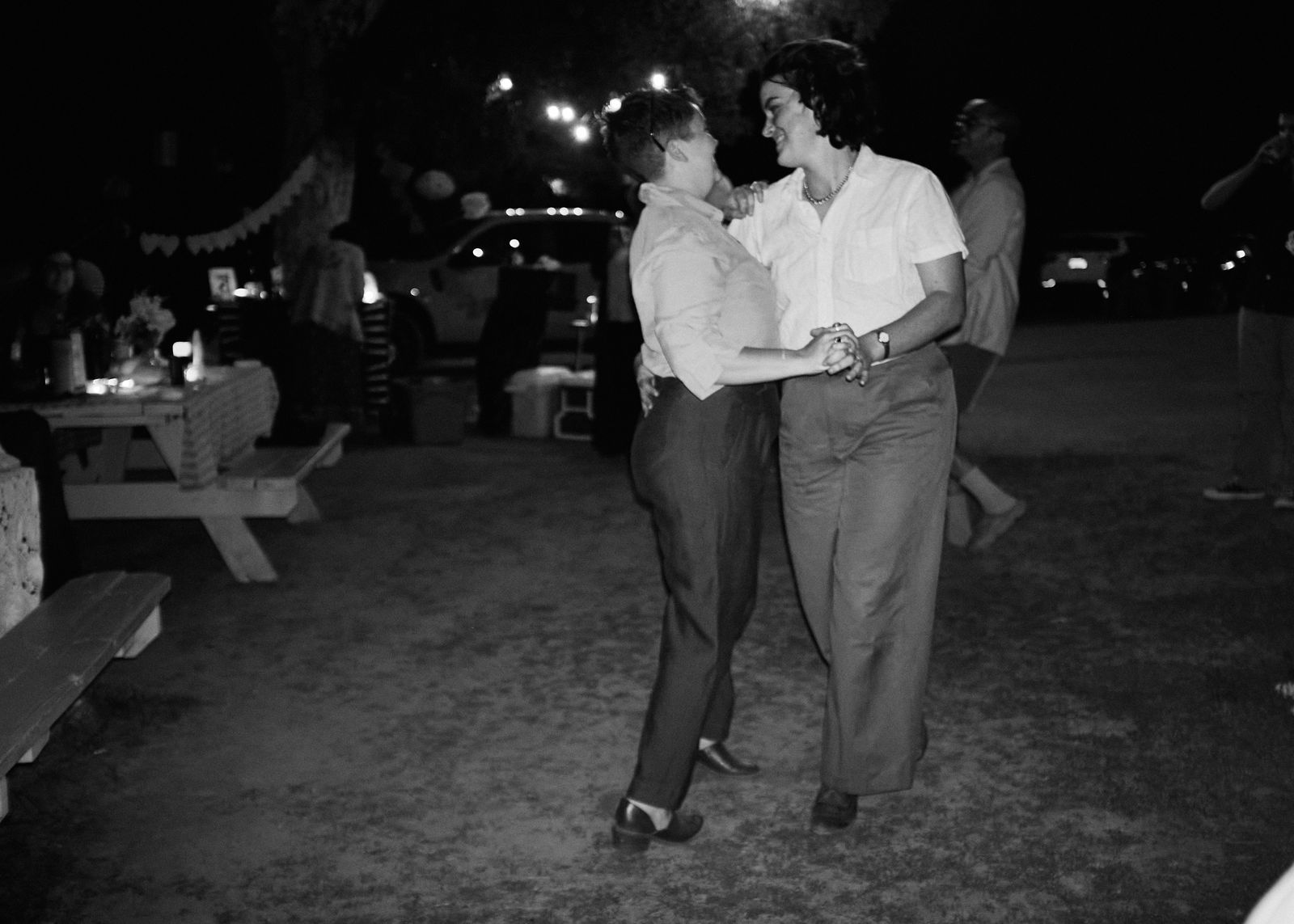 Black-and-white photo of the couple dancing under festoon lights
